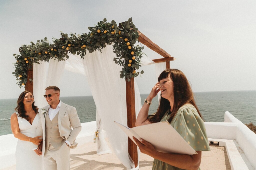 Image shows outdoor wedding ceremony in The Algarve with the bride and groom smiling